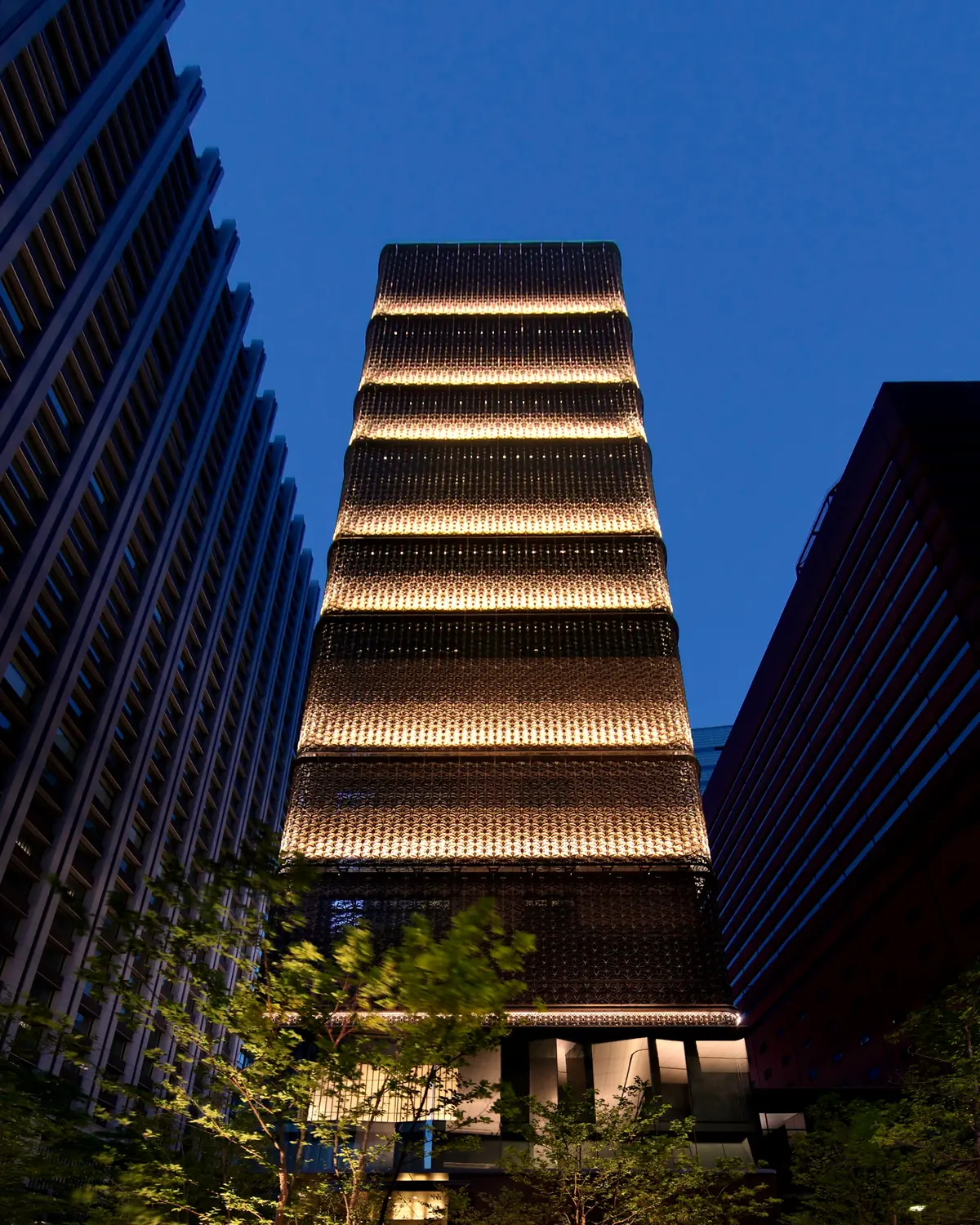 Hoshinoya Tokyo at dusk in Otemachi: the lattice-clad tower lit between office buildings