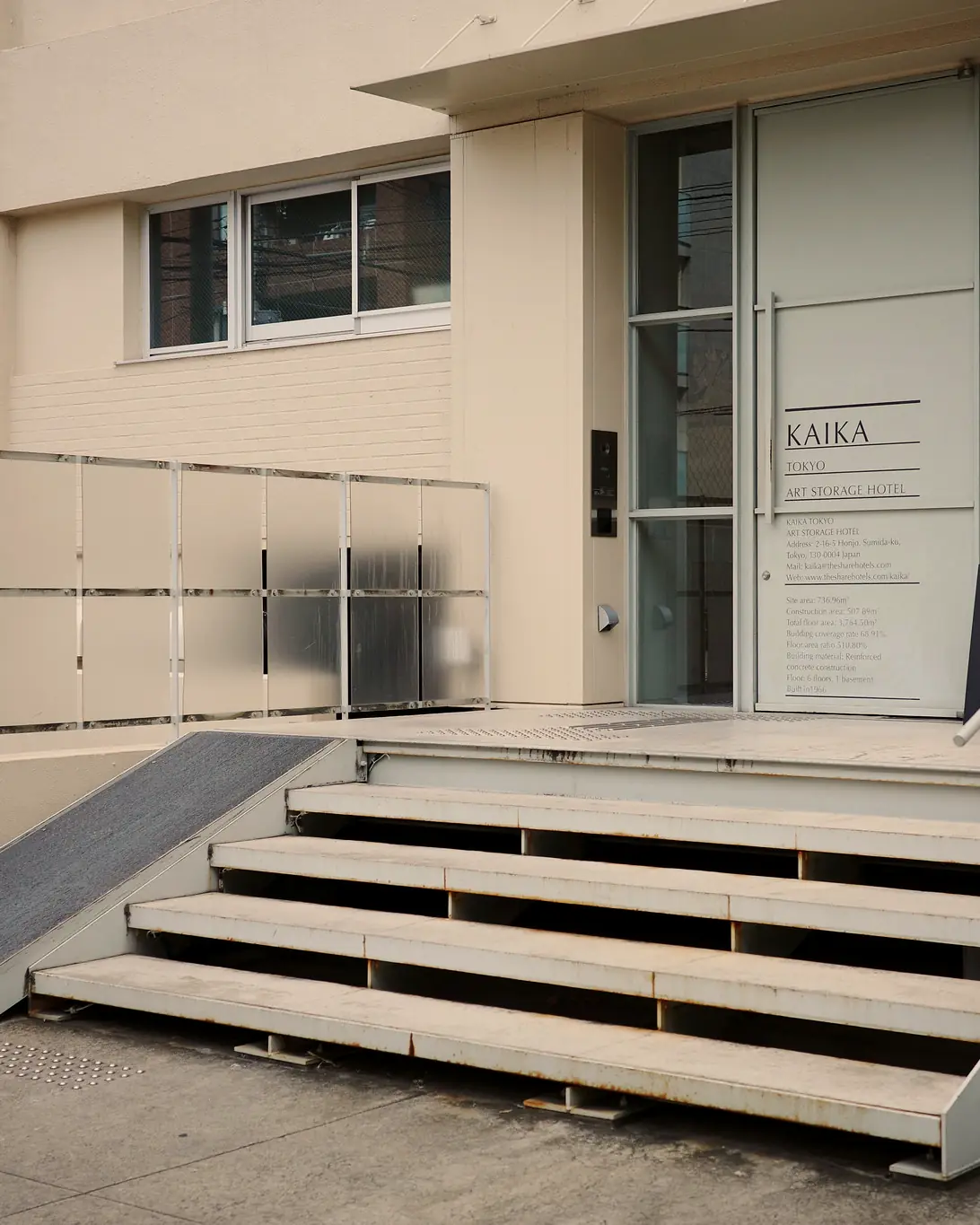 Entrance of the hotel: steps and ramp up to a glass door lettered 'KAIKA Tokyo Art Storage Hotel'