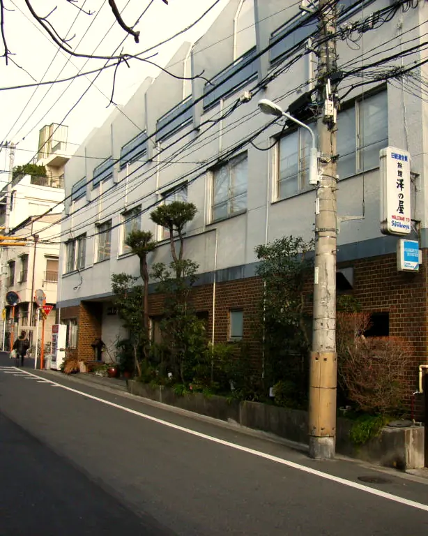 The street front of Sawanoya Ryokan in Yanaka, with a hanging sign on a grey two-storey building