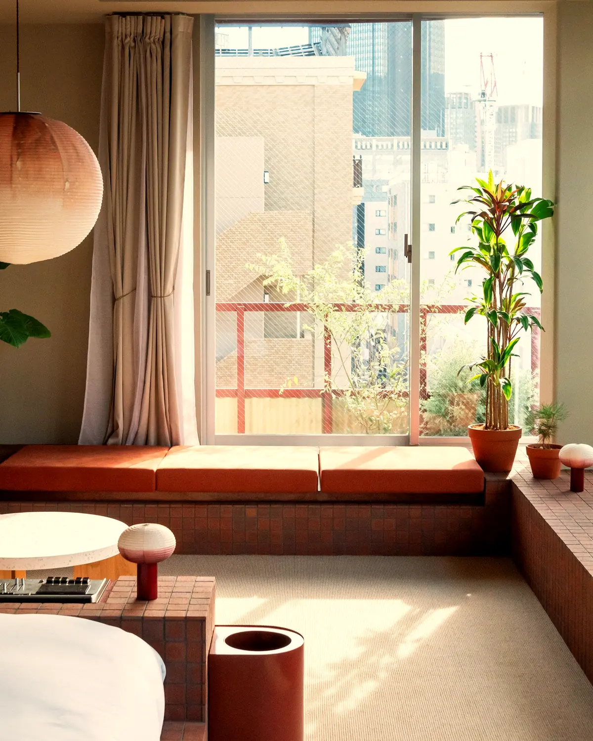 A guest room at SOIL Nihonbashi Hotel: brick window seats, plants, and a view over Ningyocho
